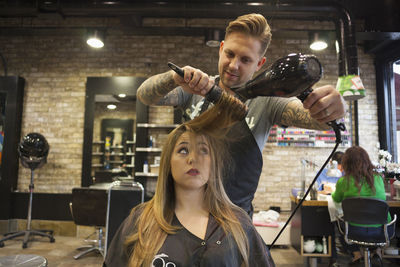 Portrait of young woman holding camera in shop