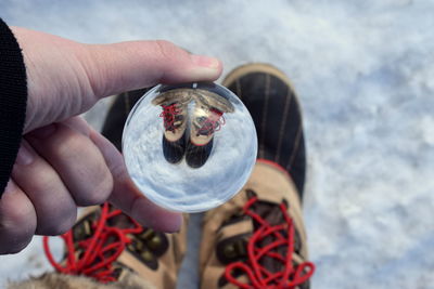 Low section of person holding crystal ball with reflection during winter