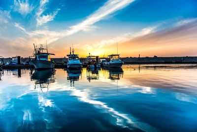 Sailboats moored in sea at sunset