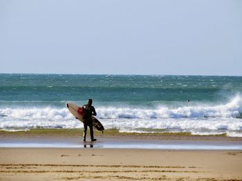 Rear view of surfer standing on shore