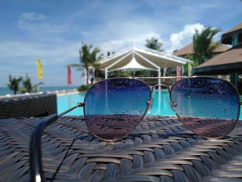 Close-up of sunglasses on chair against swimming pool