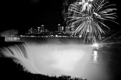 Firework display over illuminated buildings in city at night