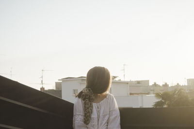 Beautiful woman looking away sitting against sky