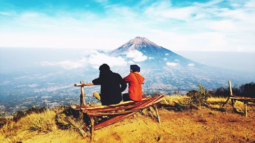 Rear view of men looking at mountains against sky