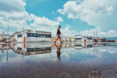 Rear view of man walking on shore against sky