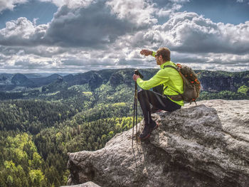 Ultralight runner.. tired sitting tourist with trekking poles in hand. sunny spring morning in rocks