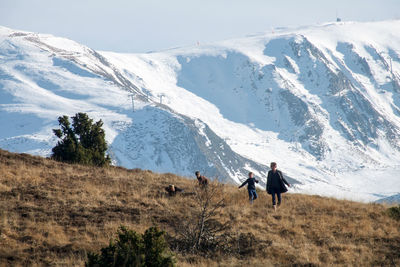 Rear view of people walking on mountain against sky