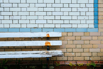 A worn and weathered wooden bench against a colorful tiled wall