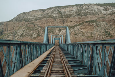 Railroad tracks by mountain against sky