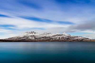 Scenic view of sea and snowcapped mountains against sky
