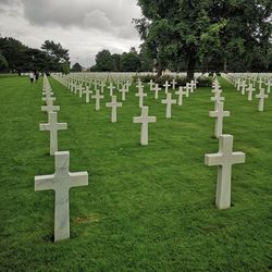 Tombstones in cemetery against cloudy sky