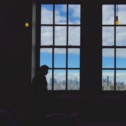 Silhouette man looking through window