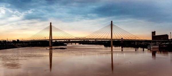 Suspension bridge over river against sky