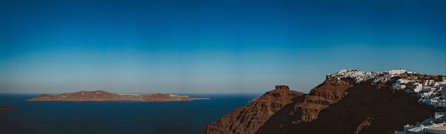 Panoramic view of sea and rocks against blue sky