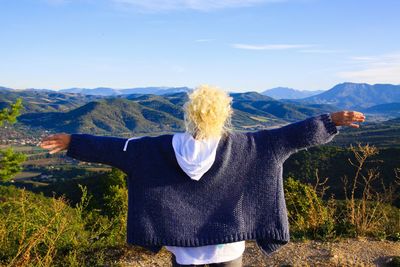 Rear view of man standing on field against mountain