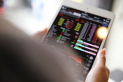 Cropped image of businesswoman analyzing stock market data on digital tablet in cafe