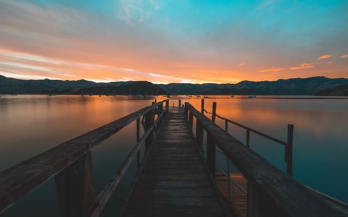 Pier over lake against sky during sunset