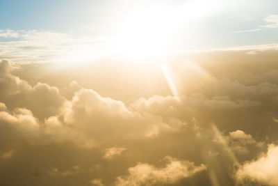 Low angle view of sunlight streaming through clouds