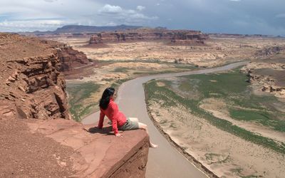 Rear view of woman on landscape against cloudy sky