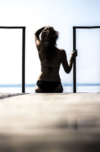 Rear view of woman standing by sea against sky