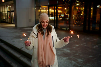 Portrait of young woman holding sparkler at night