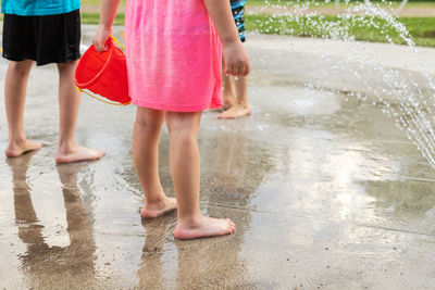 Low section of women walking on wet shore