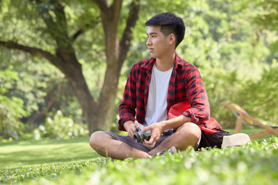Man holding mobile phone while sitting on grass
