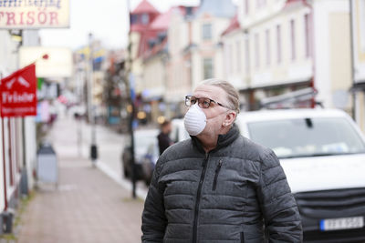 Portrait of young man standing on city