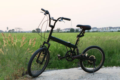 Bicycle parked on field against clear sky