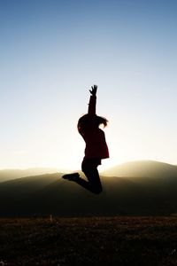 Full length of silhouette woman jumping against clear sky