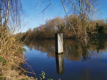 Wooden posts in lake against sky