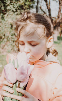 Girl smelling while holding pink tulip flowers