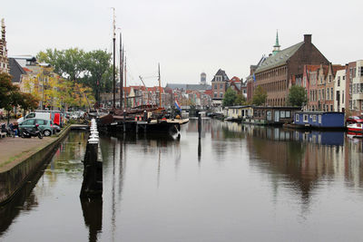 Boats moored in harbor against sky in city