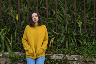 Portrait of young woman standing against plants