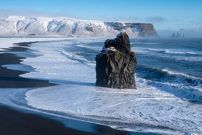 Statue of frozen sea against sky during winter