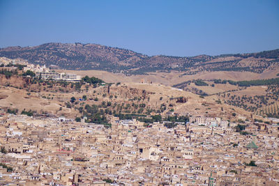 Aerial view of townscape and mountains against clear blue sky
