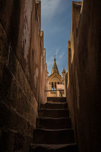 Low angle view of steps amidst buildings against sky