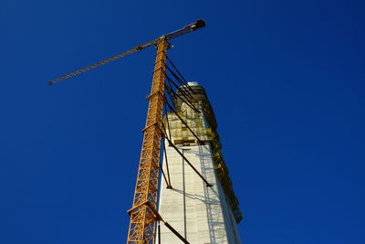 Low angle view of crane against clear blue sky