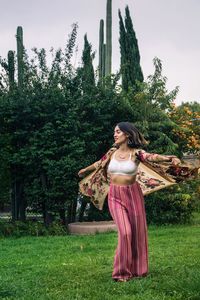 Young woman spinning while standing with arms outstretched on grass