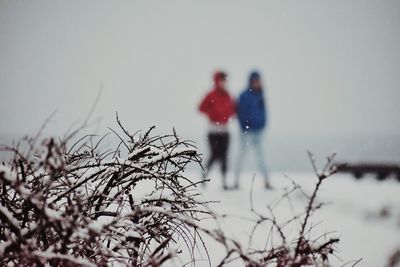 People on snow covered land against sky