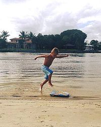 Full length of shirtless man jumping on beach