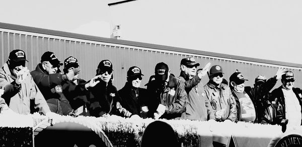 Group of people standing against built structure against clear sky