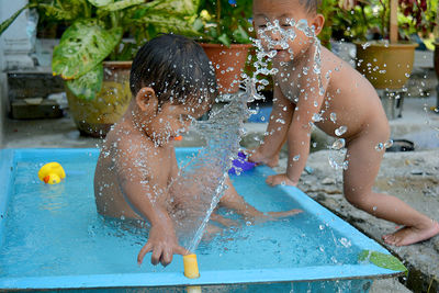 Full length of boy playing with swimming pool in yard