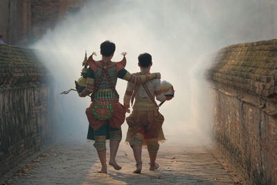 Rear view of people walking on road during foggy weather