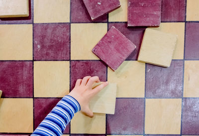 Directly above shot of child hand on multi colored tiled floor