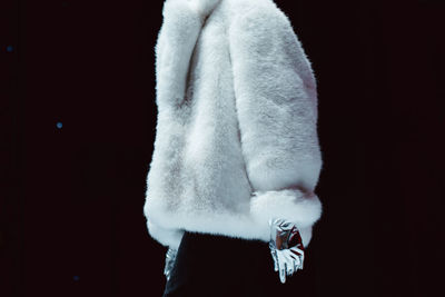 Fashion details of a white fluffy winter fur coat and silver gloves. fashion model walking