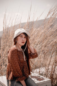 Young woman wearing hat standing on field against sky