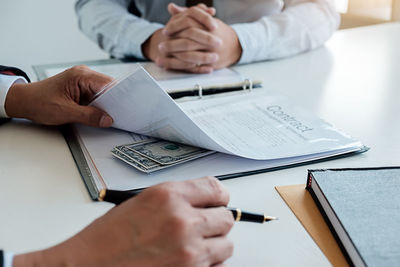 Low section of man and woman reading book on table