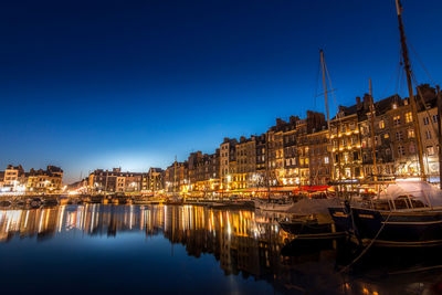 Sailboats moored in canal against buildings at night