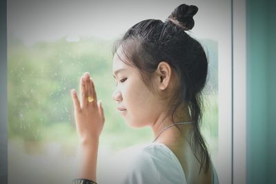 Close-up of thoughtful woman looking through window